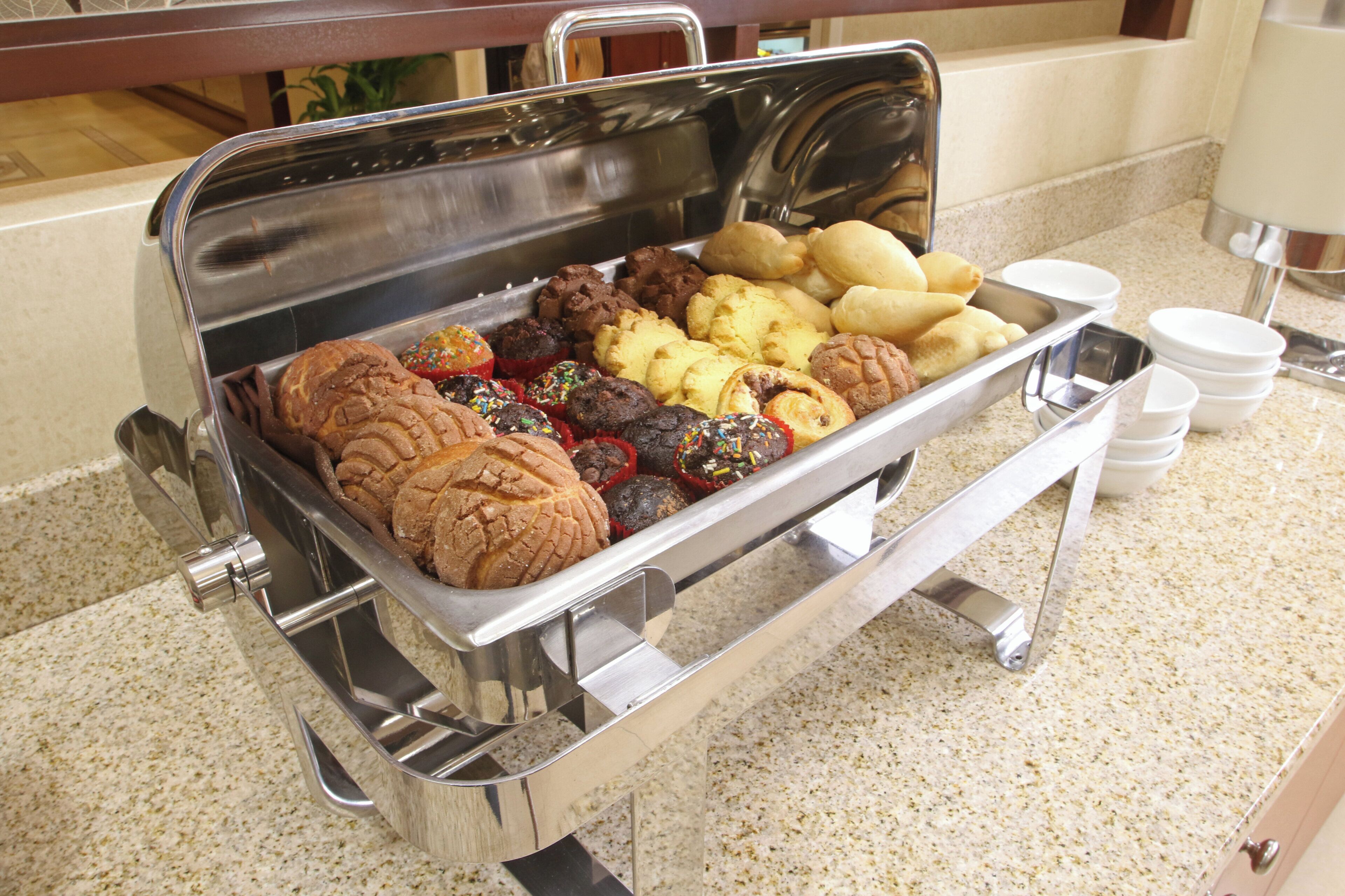 Una mesa de buffet con diferentes productos de repostería y una estación de café.