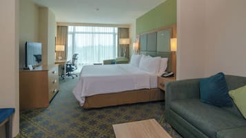 A hotel room with a bed, a desk with a computer, a chair, a couch, and a television.
