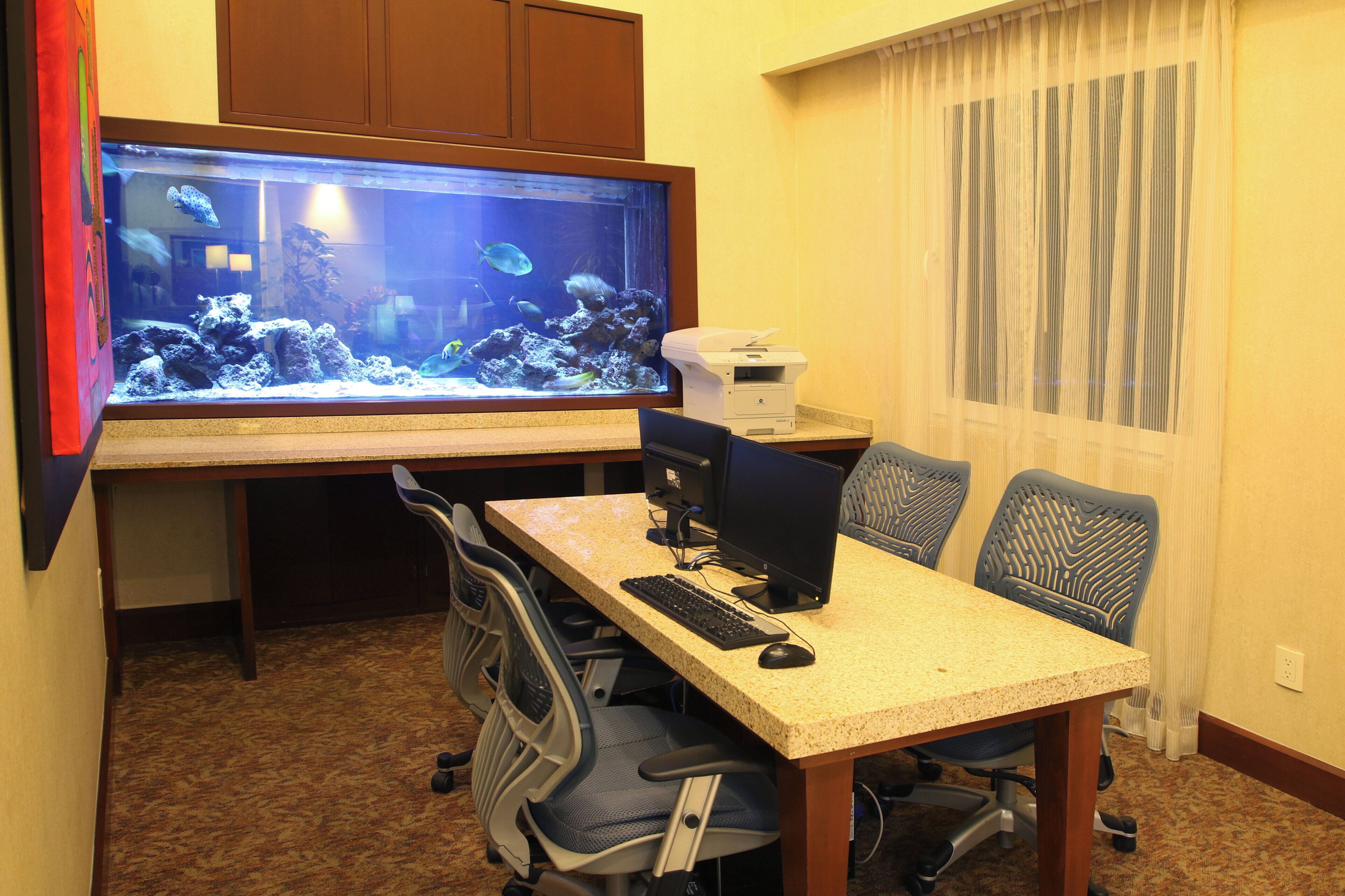 Habitación de hotel con escritorio, computadora y un acuario.
