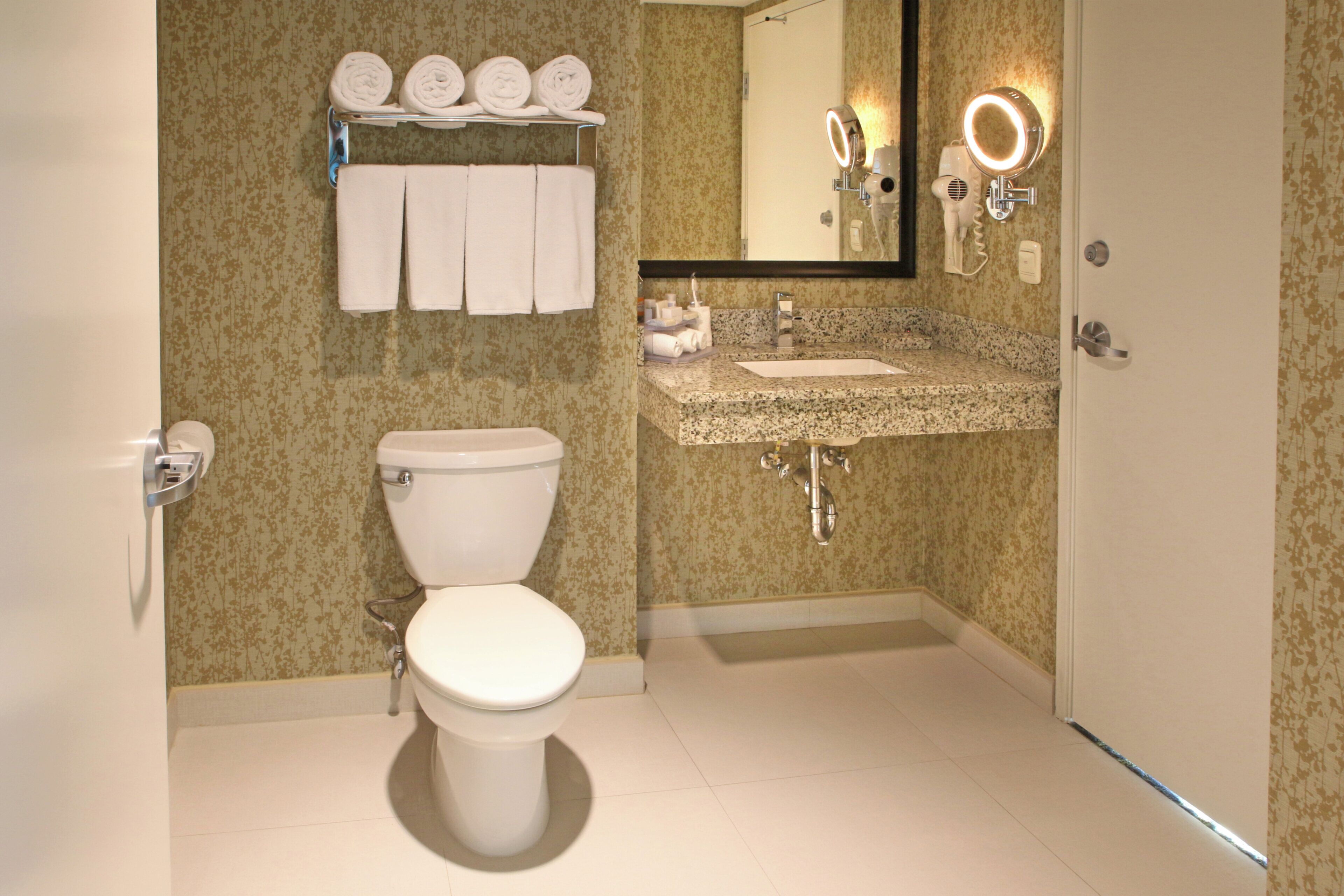 A bathroom with a toilet, sink, and towel rack with towels.