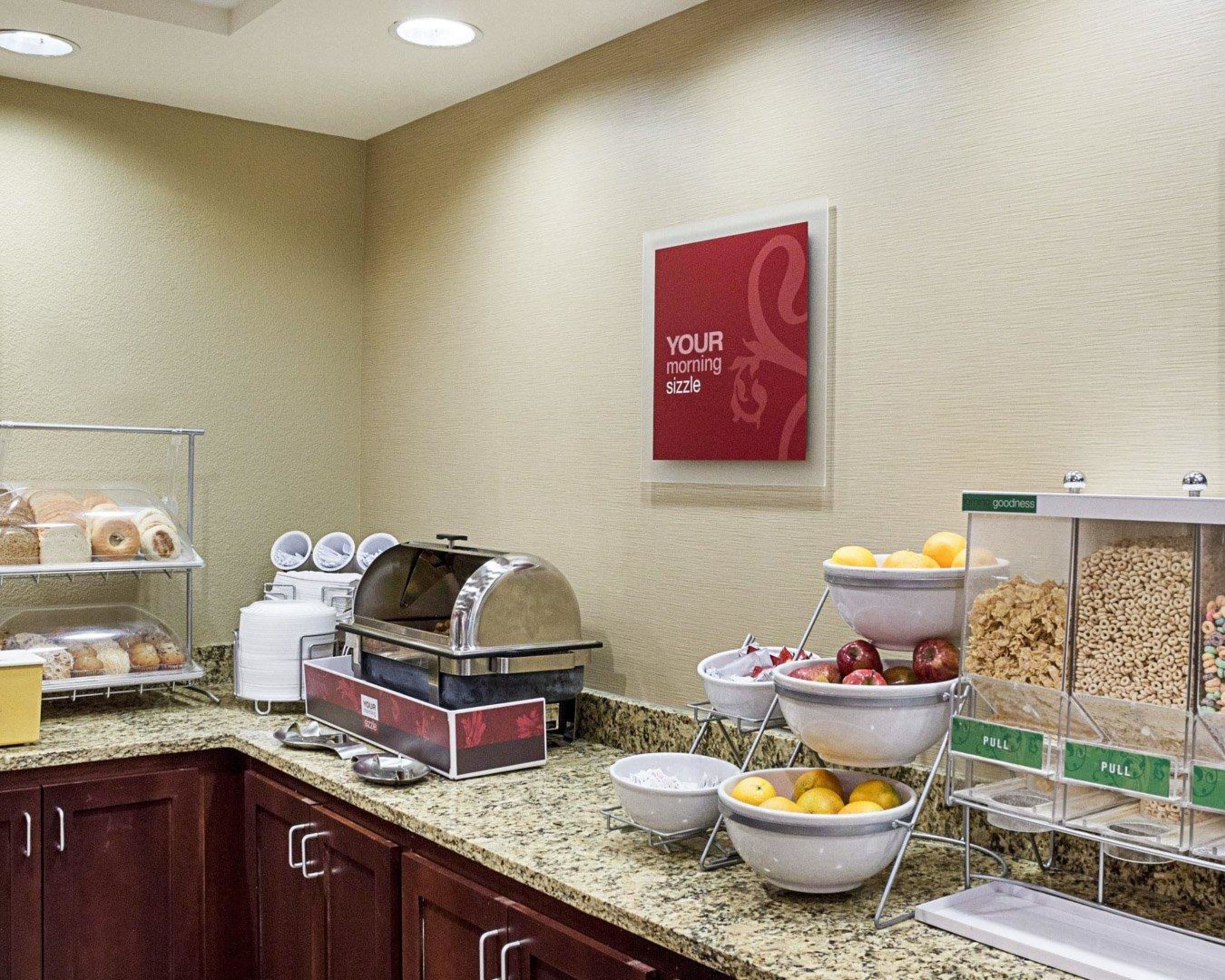 A breakfast buffet with various food items, a coffee machine, and a sign that reads "YOUR morning sizzle".