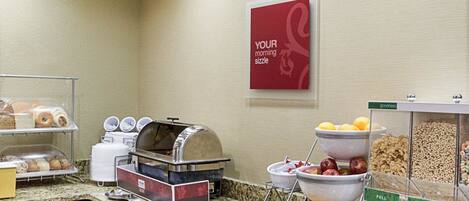 Un bufé de desayuno con diversas opciones de comida, una máquina de café y un cartel que dice 'YOUR morning sizzle'.
