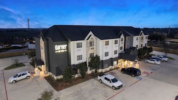 A multi-story hotel with a prominent 'Garnier' sign, a parking lot with several cars, and a view of the surrounding landscape.