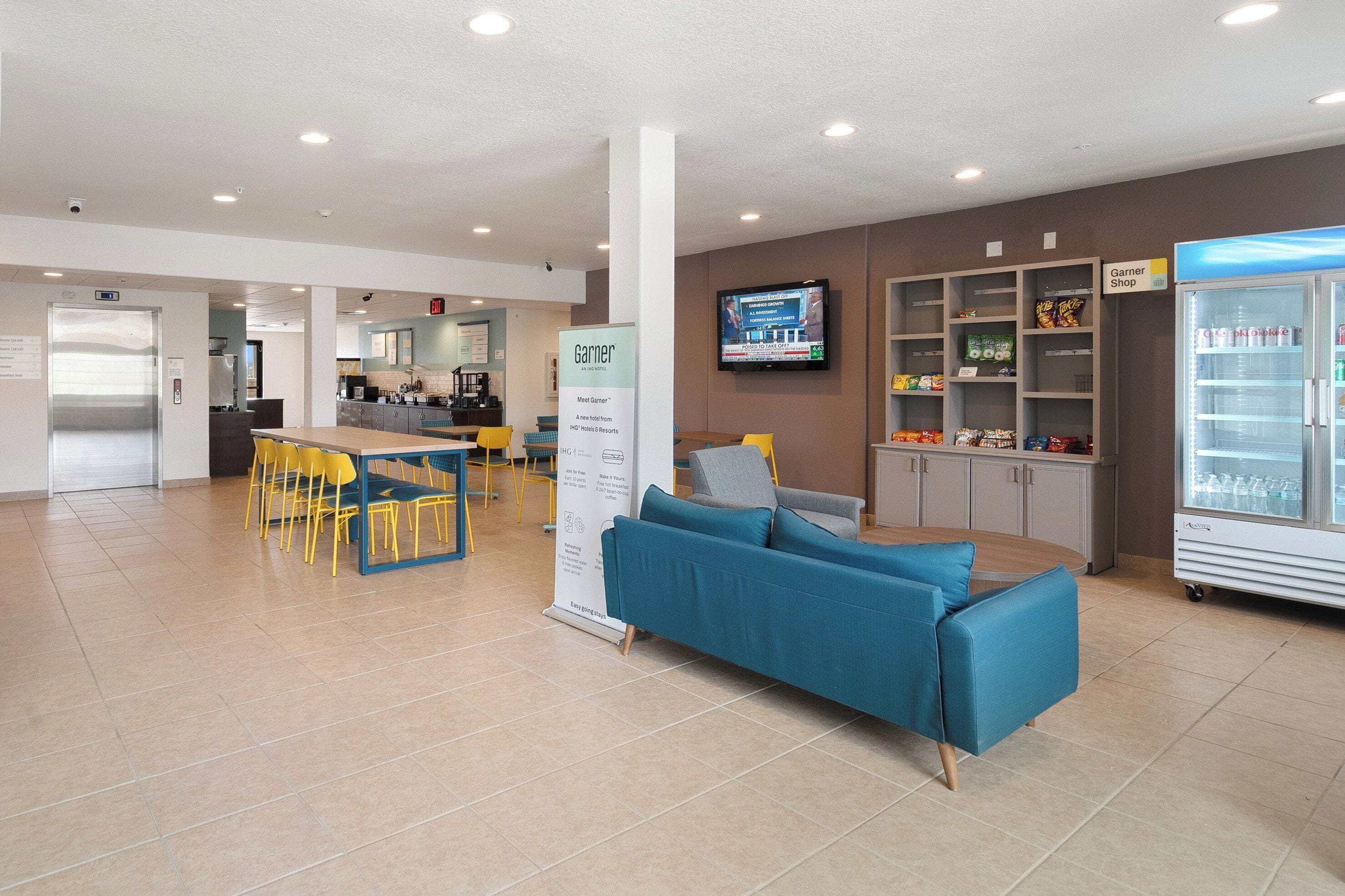 A hotel lobby with a seating area, a refreshment bar, and a television screen.