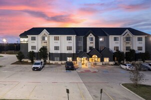 A hotel with a parking lot, multiple entry points, and a sign indicating the year 2019.