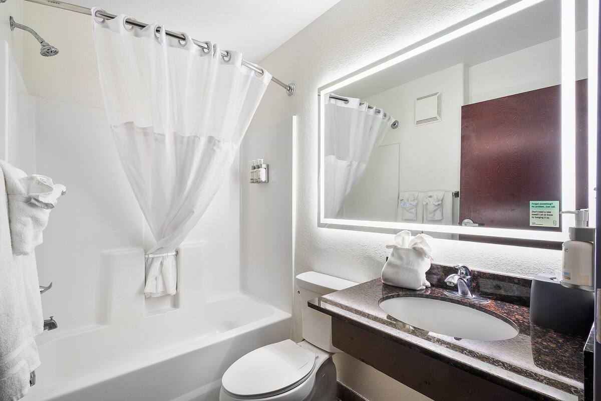 A bathroom with a bathtub, toilet, sink, and a mirror.