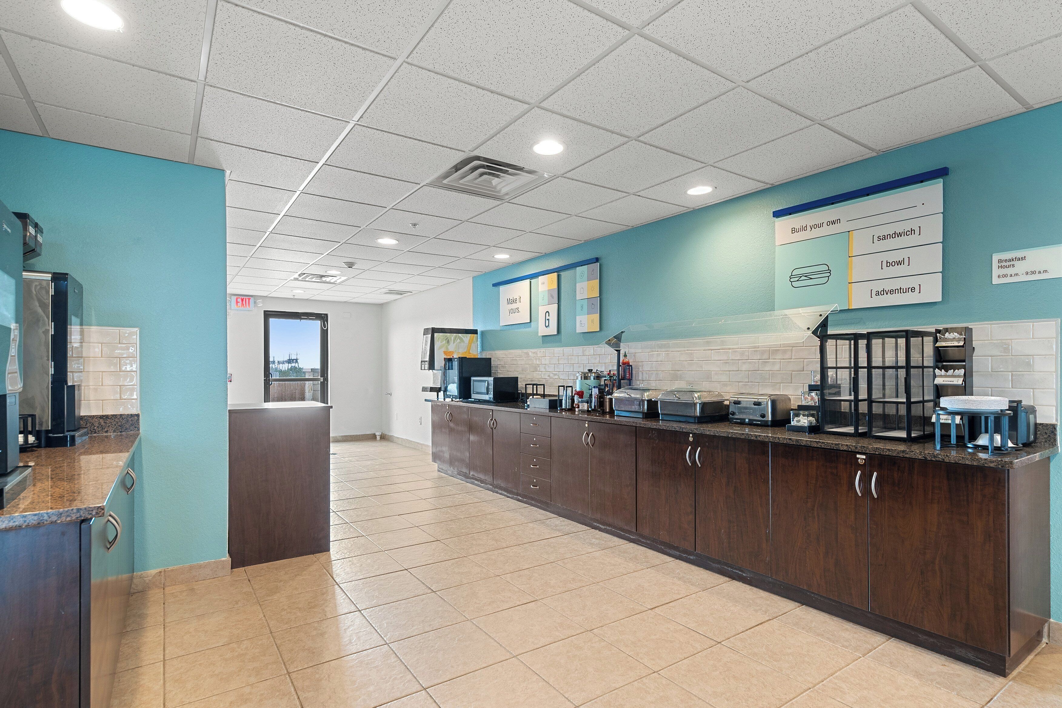 A modern kitchen with a long counter, built-in appliances, and a chalkboard menu.