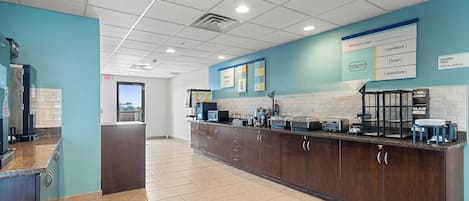 A modern kitchen with a long counter, built-in appliances, and a chalkboard menu.