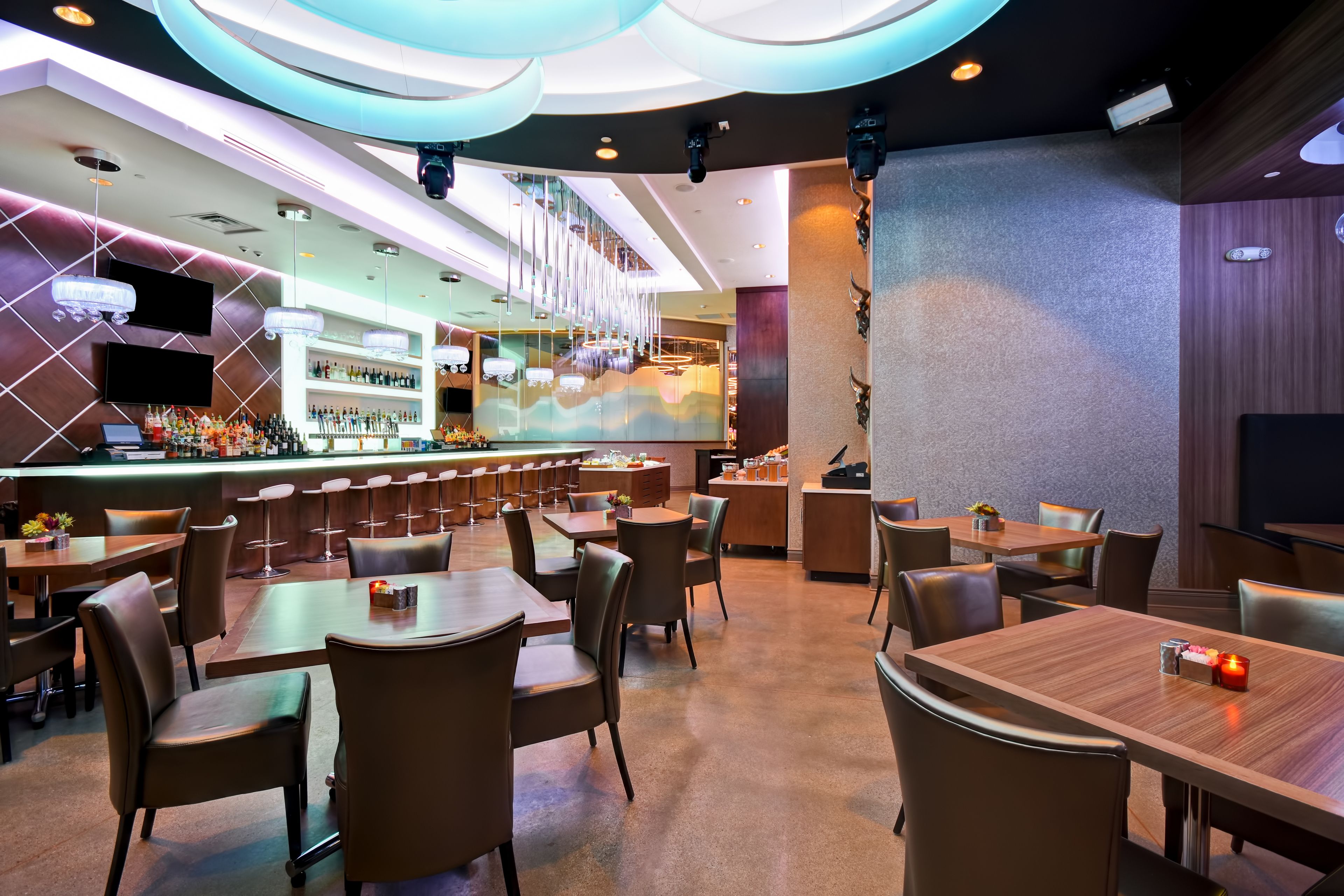 A modern restaurant with a bar area, multiple seating options, and a contemporary interior design.