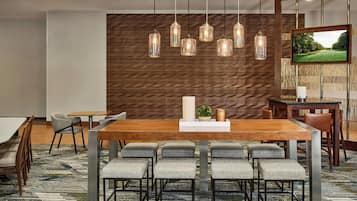 Un comedor moderno con una mesa de madera, sillas tapizadas y lámparas colgantes.