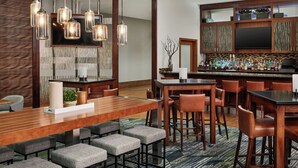 Un comedor moderno con una mesa de madera larga, sillas acolchadas y lámparas colgantes.