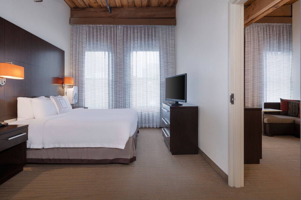 A hotel room with a bed, a TV, a desk, and a sofa.