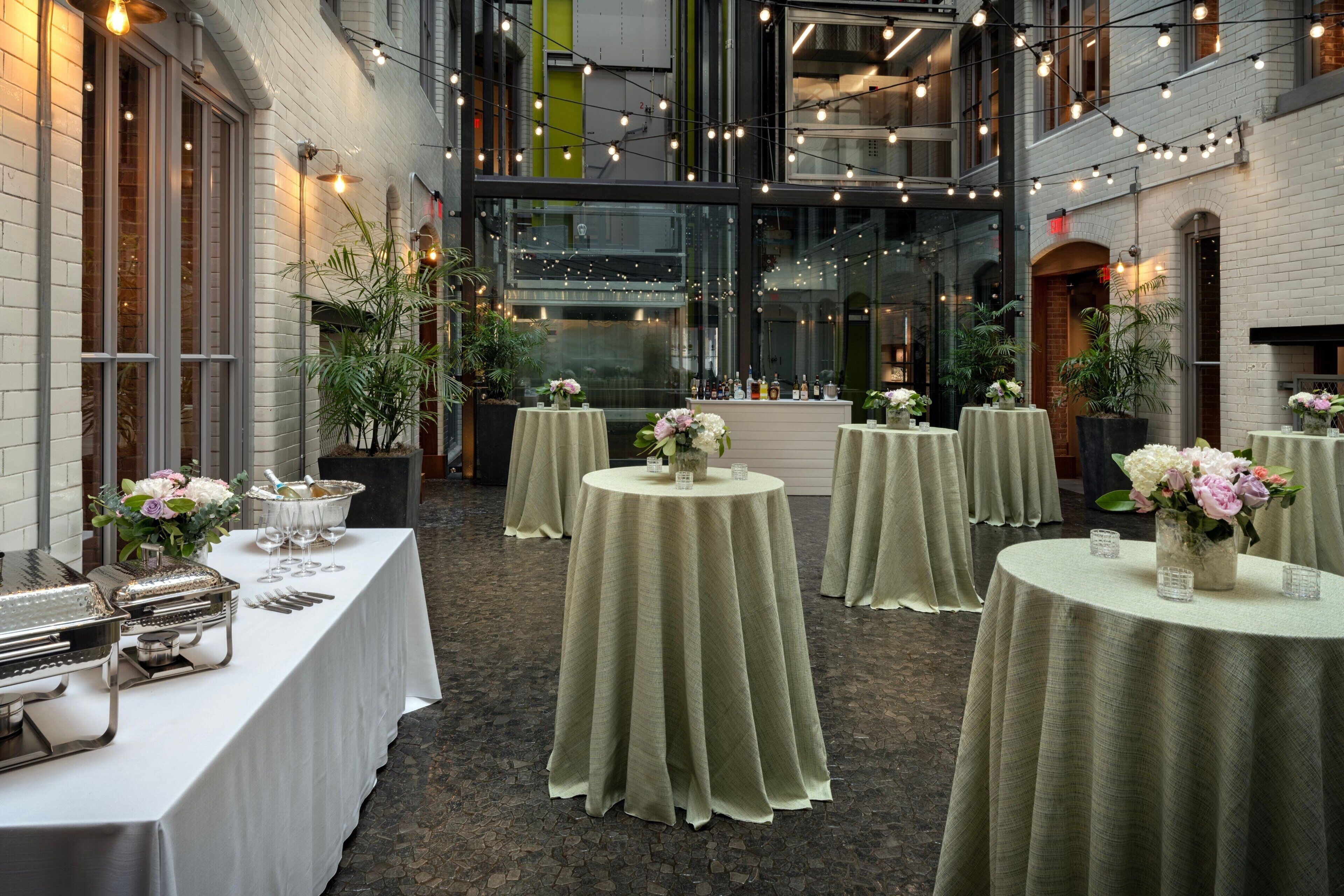 A banquet hall with round tables set for a formal event, featuring floral centerpieces and table settings.