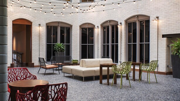 A courtyard with string lights, outdoor seating, and a brick building facade. - Residence Inn by Marriott Boston Downtown/Seaport (Boston)