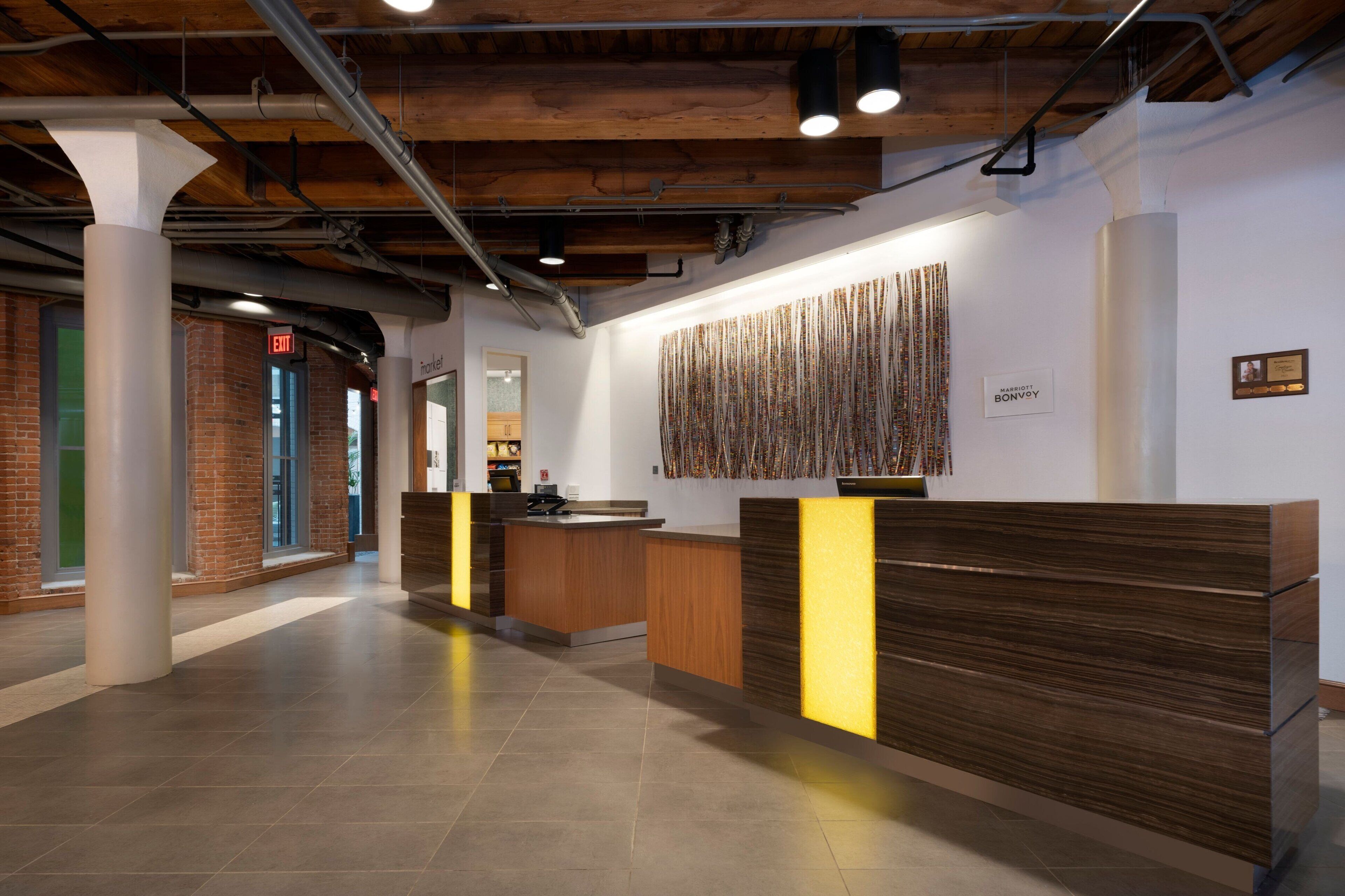 A reception area with a wooden reception desk, a patterned wall decoration, and a visible exit sign.