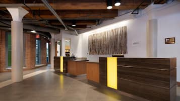 A reception area with a wooden reception desk, a patterned wall decoration, and a visible exit sign.