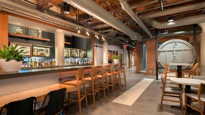 A modern bar area with wooden chairs and tables, a bar counter with bottles, and a large clock on the wall. - Residence Inn by Marriott Boston Downtown/Seaport (Boston)