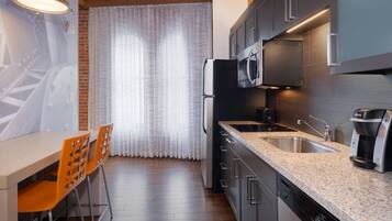Una cocina moderna con encimera de granito, electrodomésticos de acero inoxidable y un comedor con mesa y sillas.