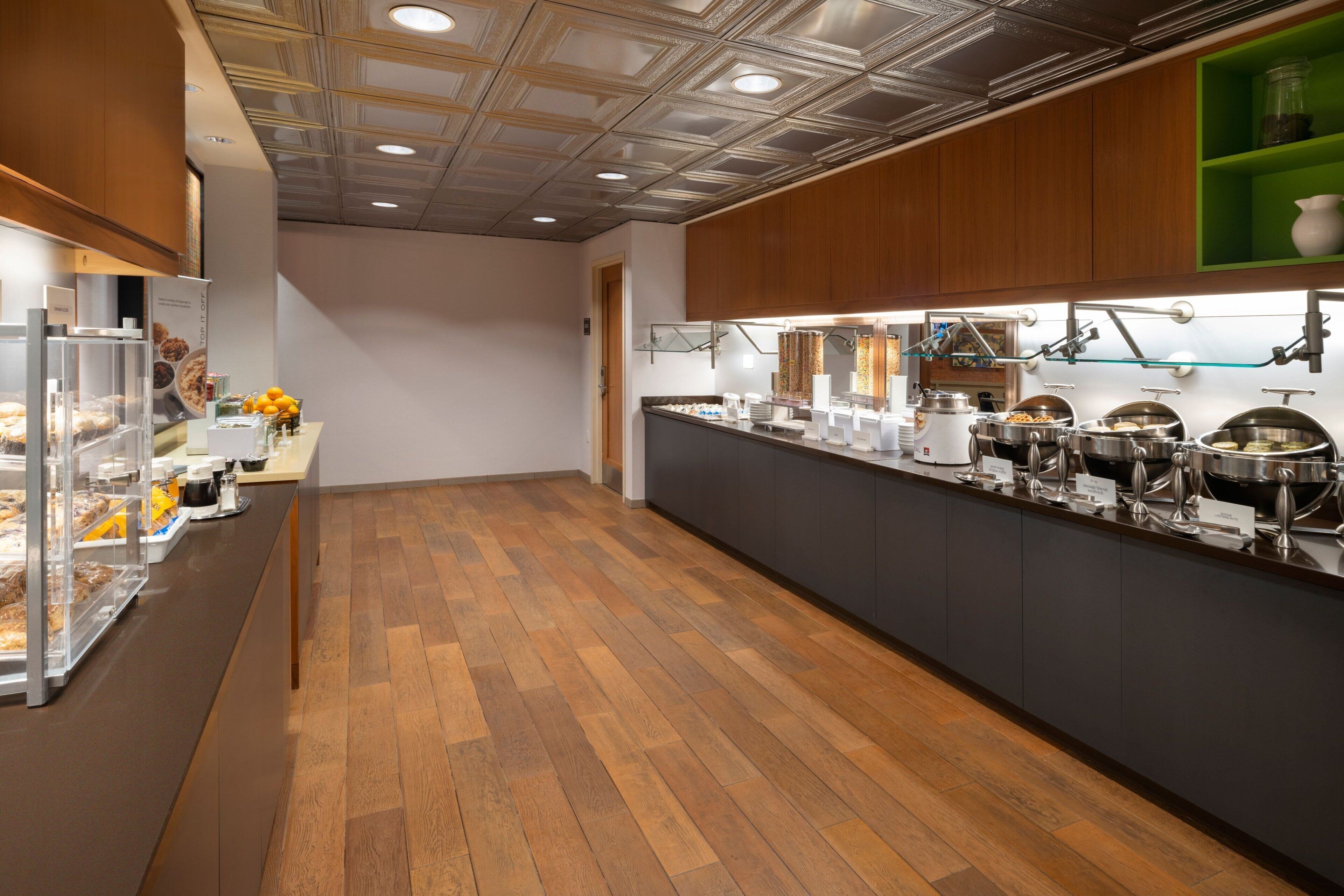 A buffet area with a wooden floor, glass display cases, and a variety of food items.