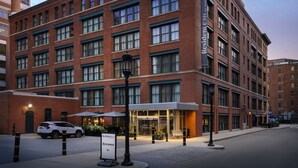 A brick building with a modern entrance, a white car parked in front, and a sign indicating the entrance. - Residence Inn by Marriott Boston Downtown/Seaport (Boston)