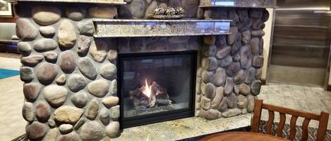 A stone fireplace with a fire, surrounded by a stone wall.