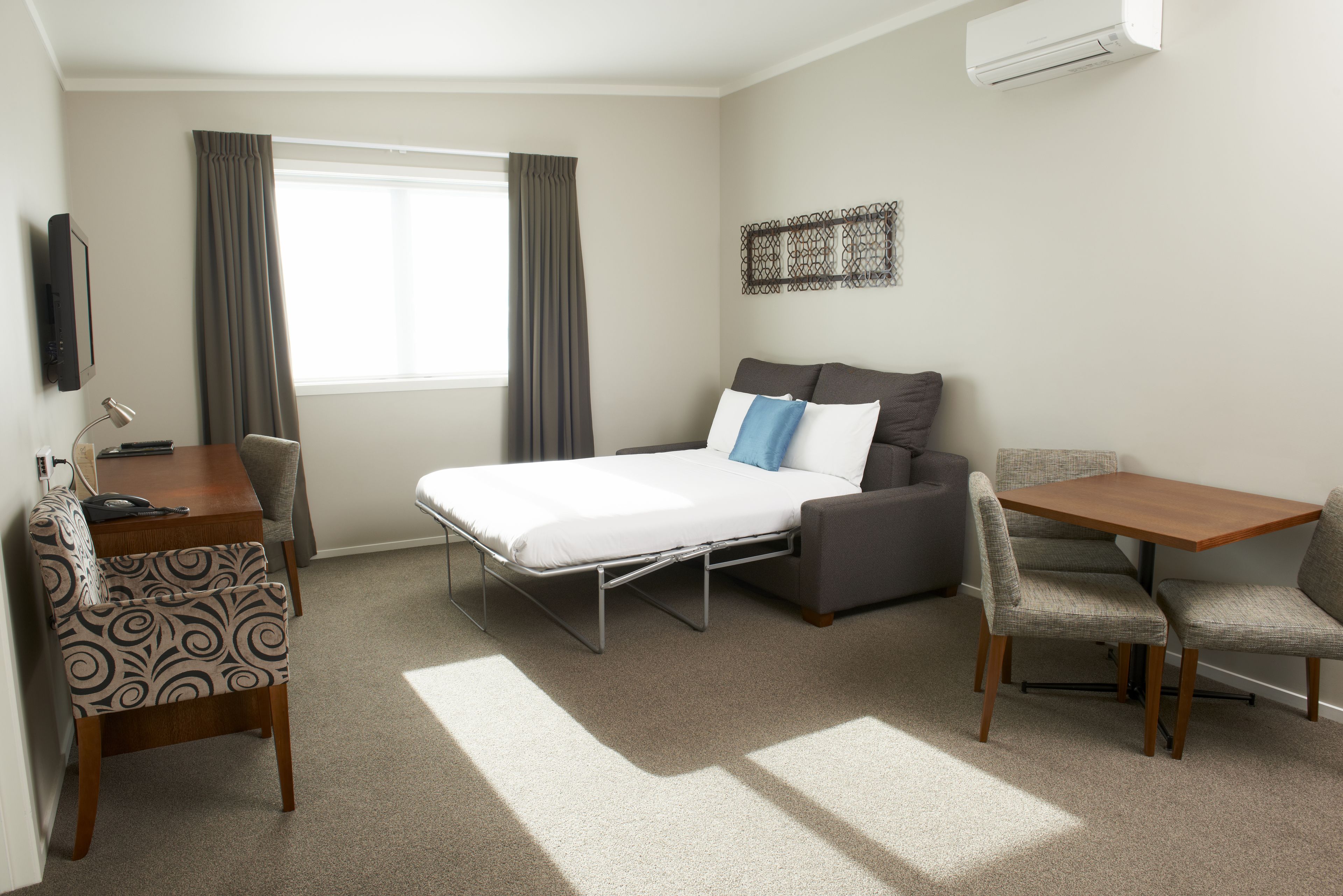 Une chambre d’hôtel équipée d’un lit, d’un bureau, d’une chaise, d’une table et d’un téléviseur.