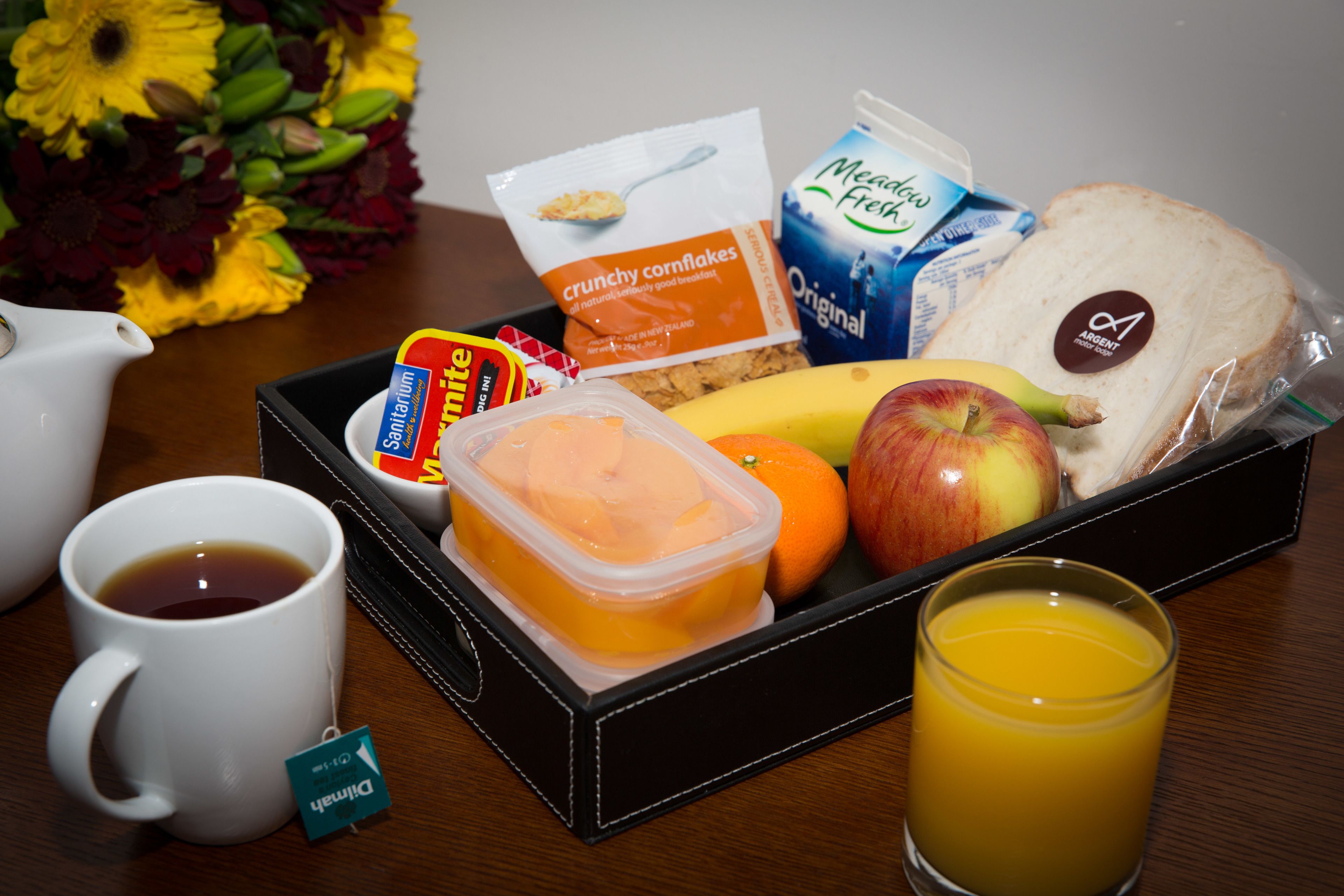 Bandeja de desayuno con pan, frutas, jugo y una taza.