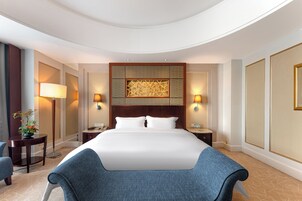 Una habitación de hotel con una cama grande, dos mesitas de noche, un escritorio, una silla y un panel decorativo en la pared.