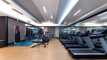 Et fitnesscenter med løbebånd, boksebold og træningsudstyr.