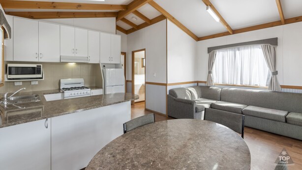 Una cocina moderna con armarios blancos, encimera de granito y comedor con mesa y sillas redondas.