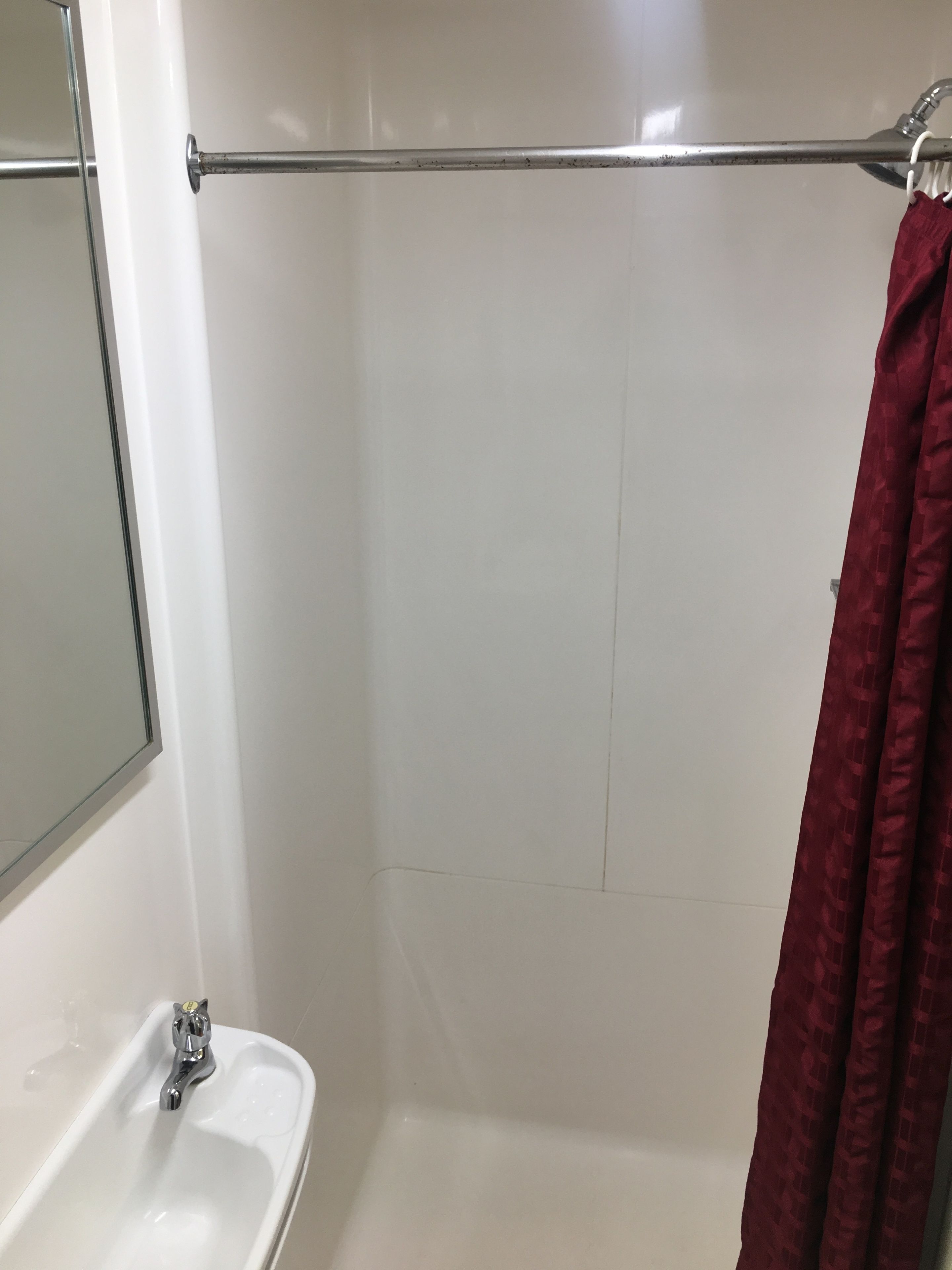 A bathroom with a white sink, a mirror, a shower with a glass door, and a towel rack.