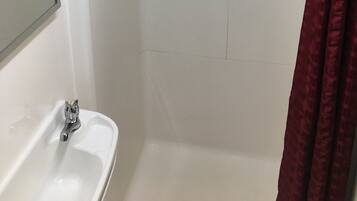 Un bagno con un lavandino bianco, uno specchio, una doccia con porta in vetro e un portascopevoli.