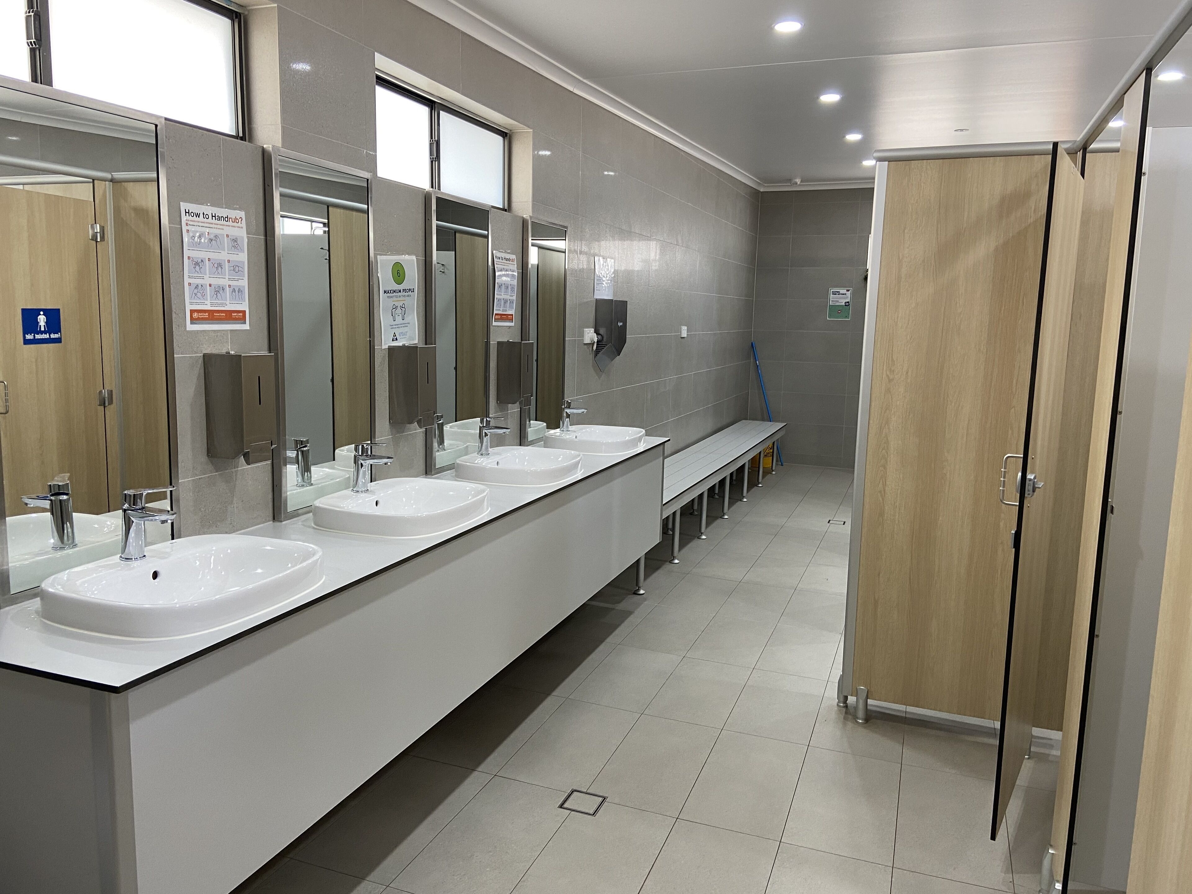 Een ruime, moderne badkamer met meerdere wastafels, spiegels en houten kastjes.