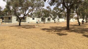A row of small, single-story buildings with a dry, grassy ground.