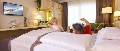 Habitación de hotel con cama, televisión, escritorio con lámpara y ventana con cortinas.