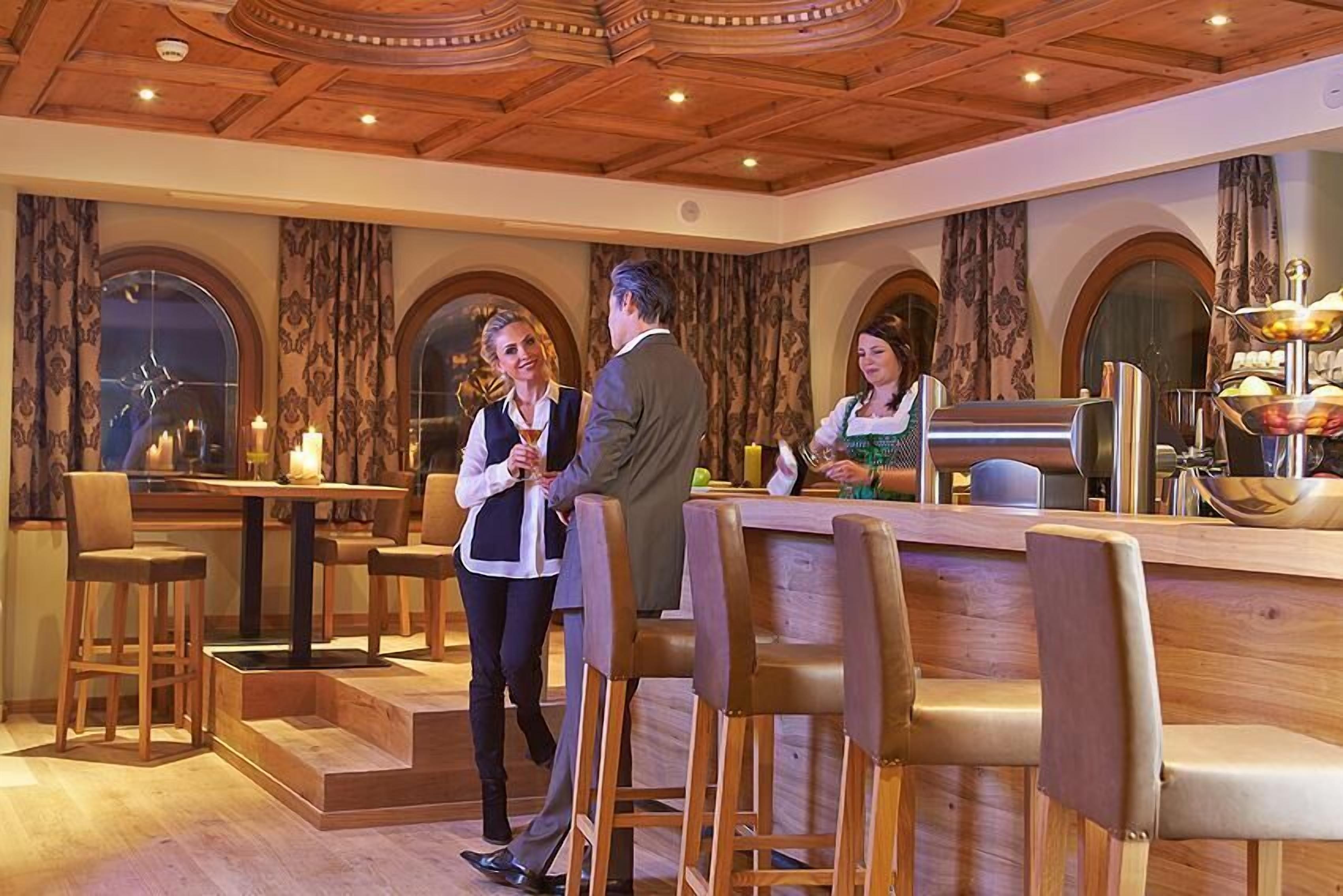 Ein Restaurant mit Holzhockern, einer Bar und einer Chandelier.