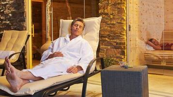 A spa room with two reclining chairs, a massage table, and a potted plant.