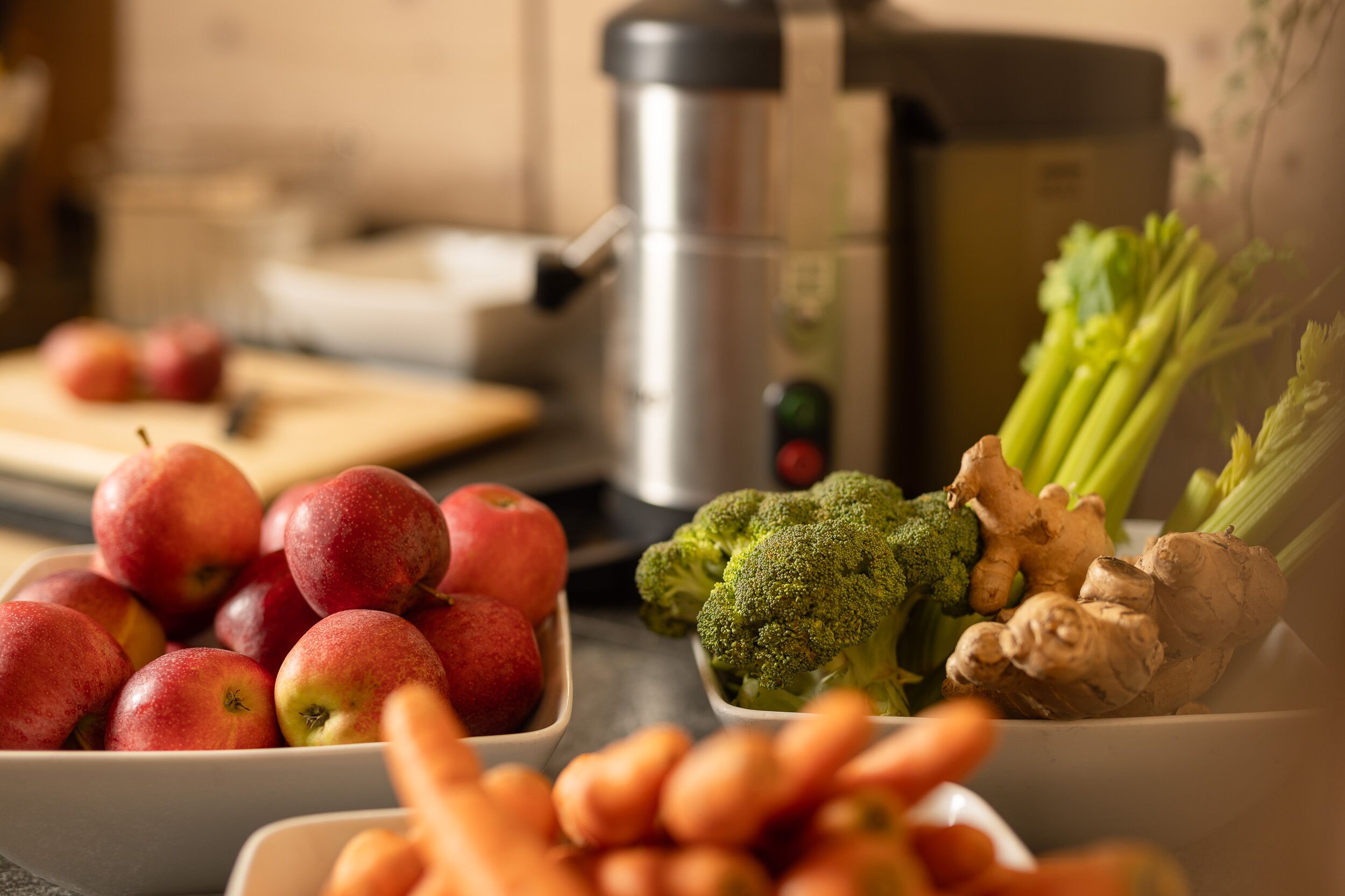 A kitchen counter with bowls of apples, broccoli, and ginger.