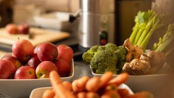 A kitchen counter with bowls of apples, broccoli, and ginger.