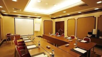 A conference room with a long table, chairs, a projector screen, and a whiteboard.