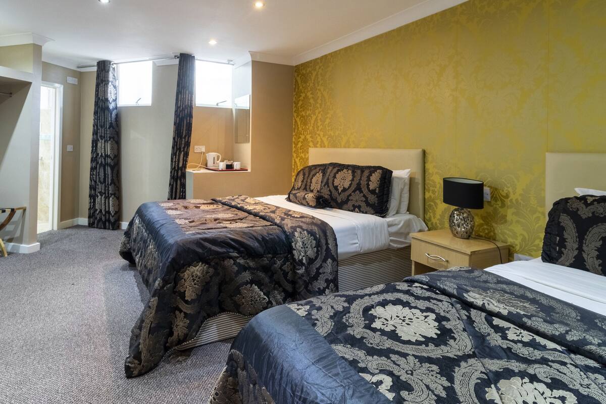 A hotel room with a large bed, a bedside table, a lamp, and a mirror.