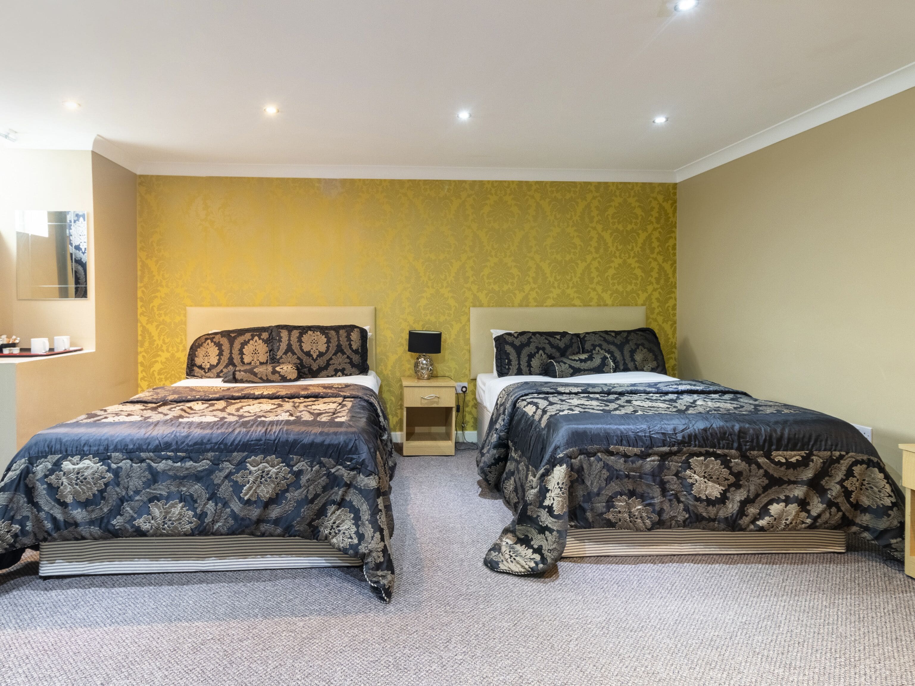 A double bed room with a yellow wall and a carpeted floor.