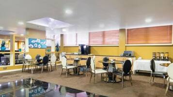 A dining area with multiple tables and chairs, a counter with a cash register, and a coffee station.