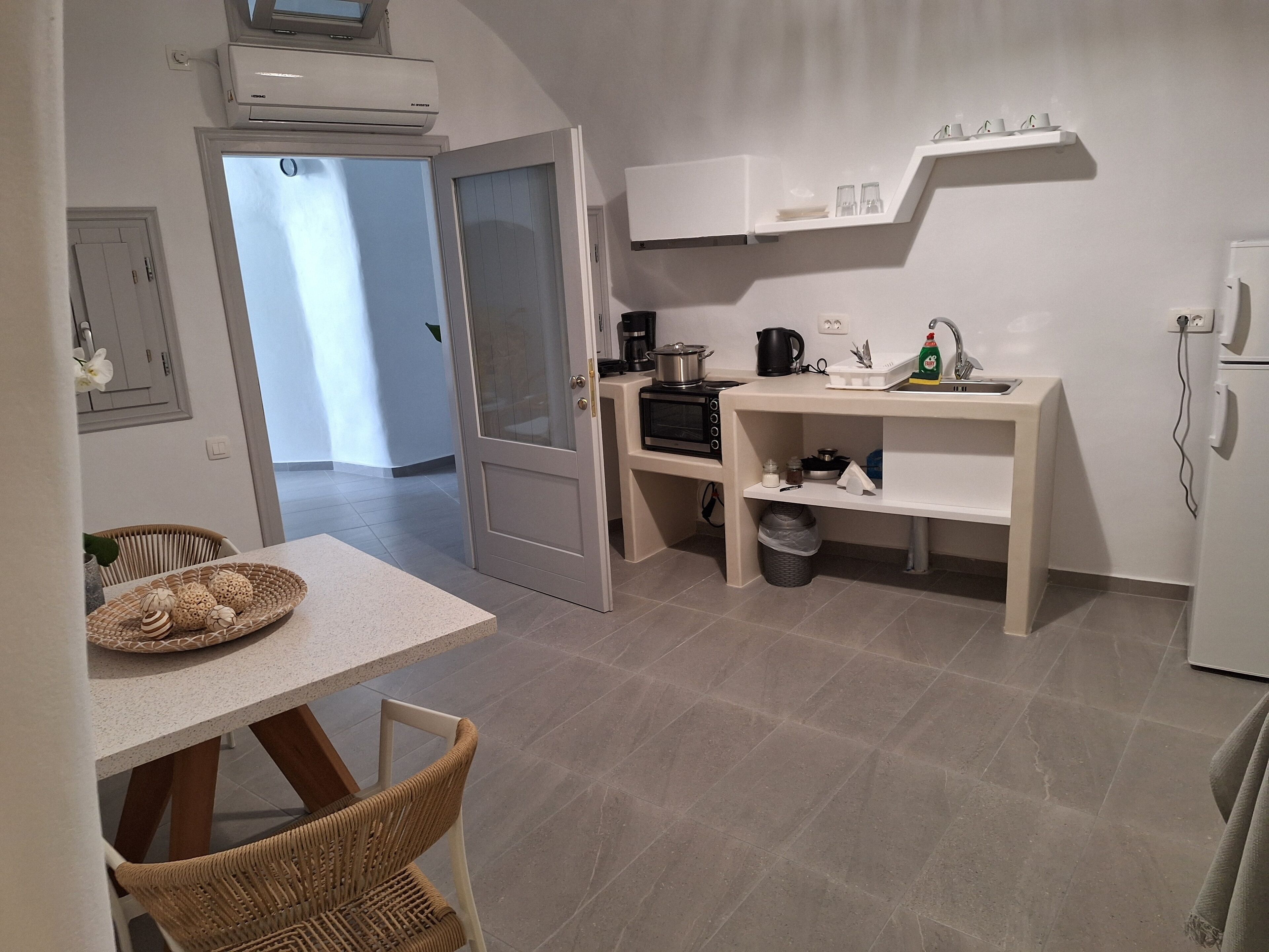 Une cuisine compacte avec un coin repas, comprenant une table avec des chaises, un four à micro-ondes, une bouilloire et un évier.