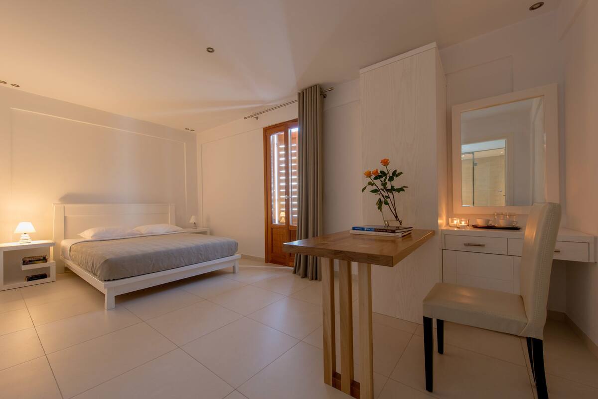 A modern bedroom with a bed, bedside table, and a desk with a chair.