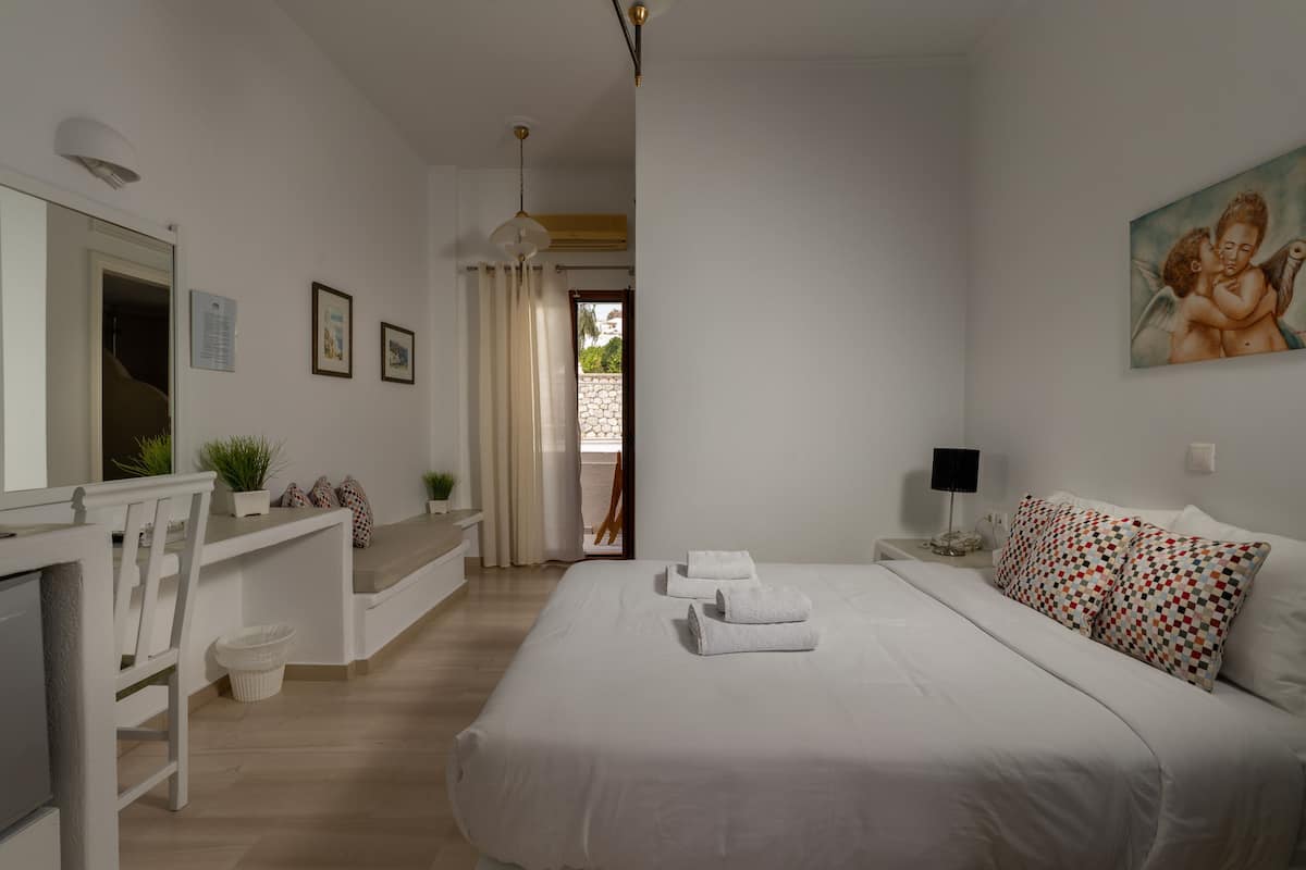 A bedroom with a bed, bedside table, lamp, and a painting on the wall.