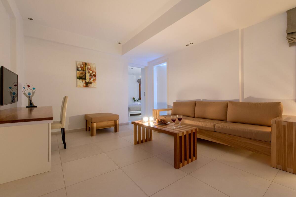 A modern living room with a sofa, a wooden coffee table, a TV, and a chair.