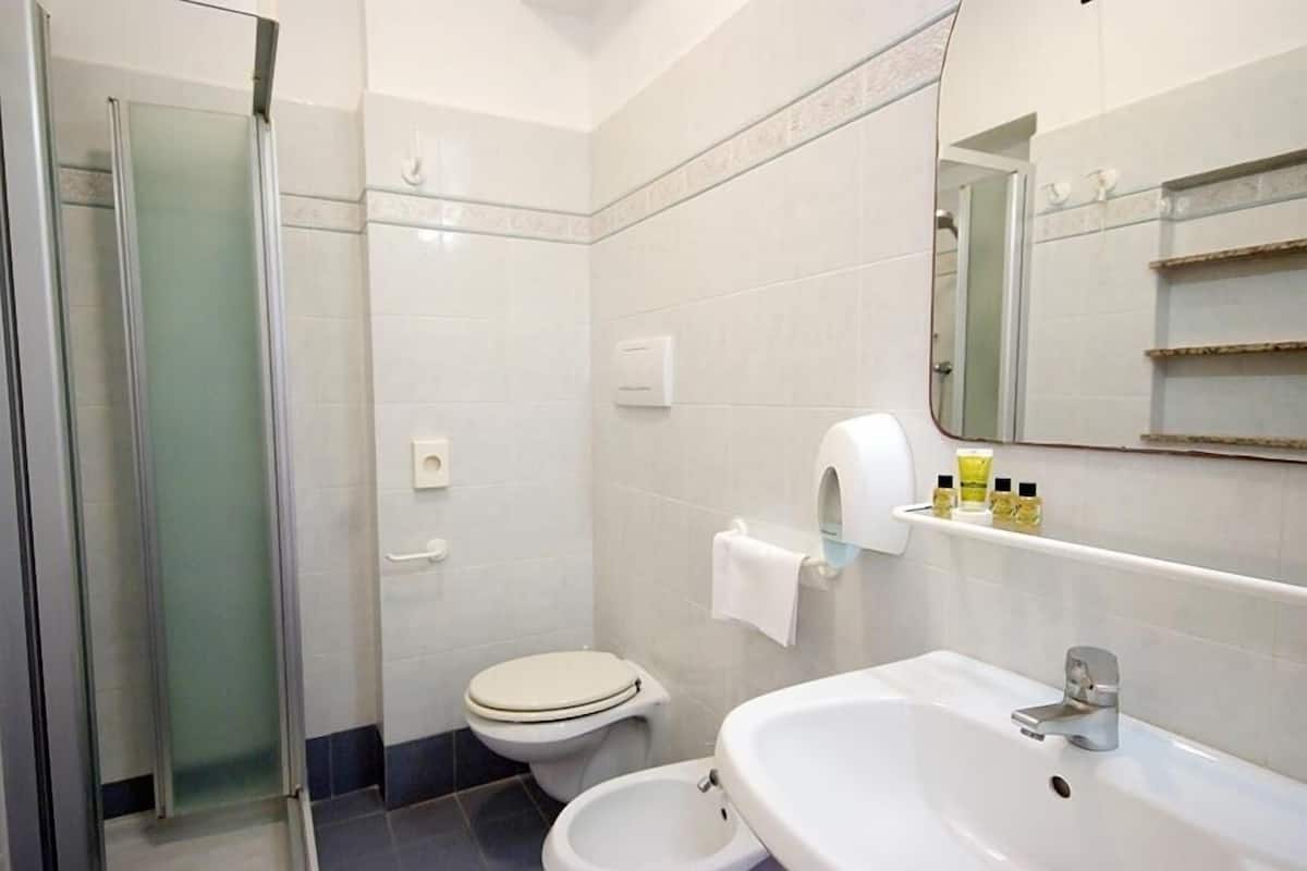 Une salle de bain avec une douche à parois de verre, des toilettes, un lavabo et un miroir.