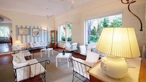 A spacious living room with a high ceiling, white walls, and large windows. There are multiple seating areas with white furniture and a central coffee table. - Hotel Brigantino (Marciana)