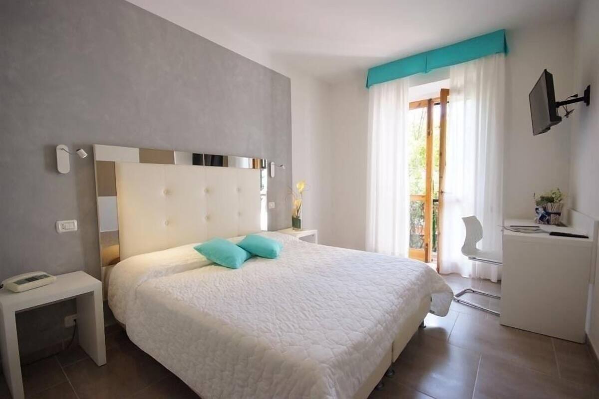 Une chambre à coucher moderne avec un grand lit, une table de chevet, un bureau et une chaise.